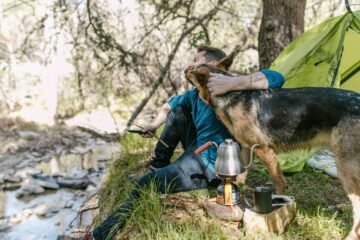 hombre acariciando a su perro, en una excursión de senderismo y acampada