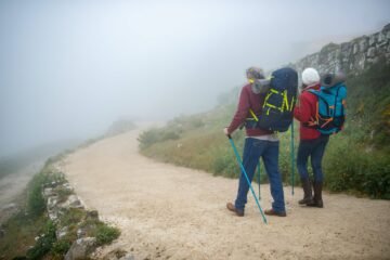 dos senderistas caminando en la naturaleza, con sus mochilas en la espalda